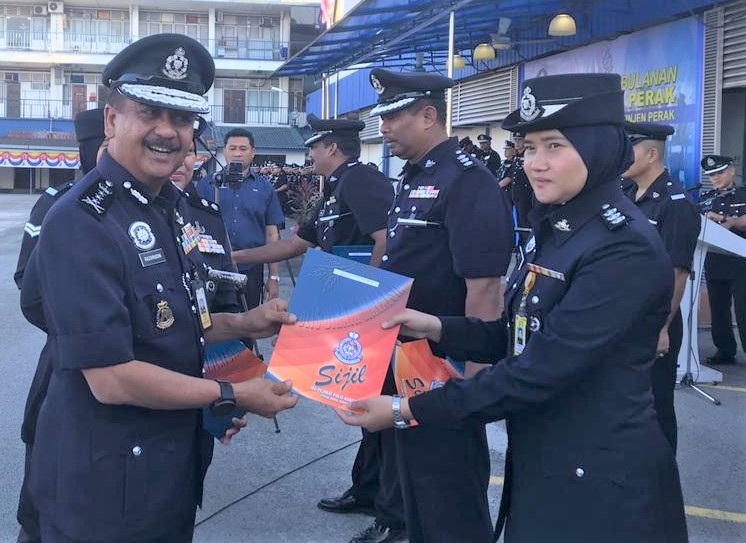霹雳州警察总部执照组警官哈扎杜（右）从纳沙鲁丁手中接过表扬状。