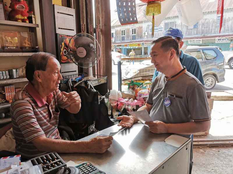 黄日升（右）拜访皇家湾老店华裔店主。