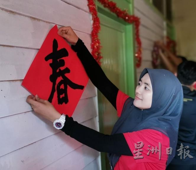 巫裔少女贴上“春”字，为华裔送上真诚的祝福。