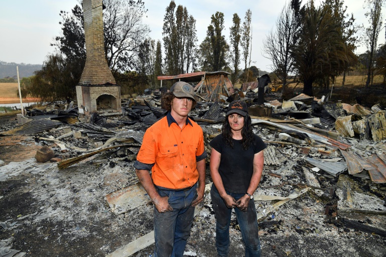 Brother and sister Jesse and Kiahan Bellchambers stand in front of the charred ruins of their home in Batlow. Photo courtesy: AFP
