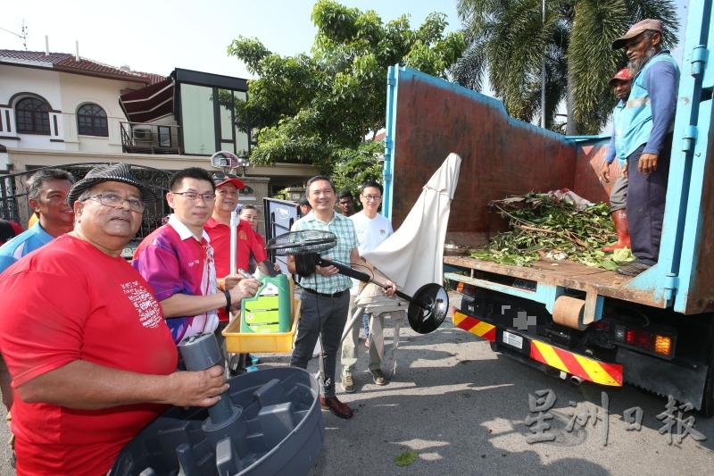 黄基全（右起）、黄思汉及叶国荣（左二）协助居民将大型垃圾搬上垃圾车。（图：星洲日报）