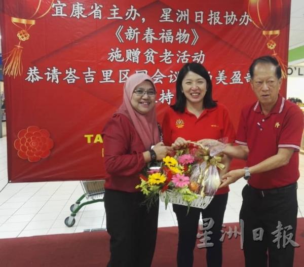 麻坡哈芝再益宜康省经理拉菲达（左）与张烈武（右）联合赠送水果礼篮给杨美盈。（图：星洲日报）