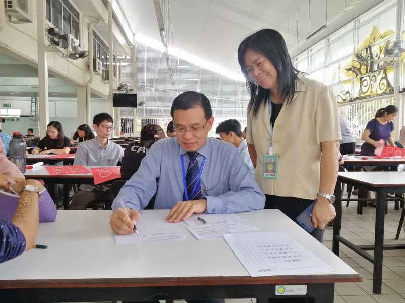 校长郑展兴（坐者）参加校内英文硬笔书法比赛。