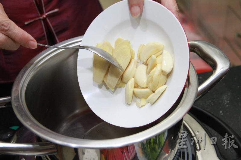 加入2汤匙油热锅，把蒜粒放入锅中，盖上盖子焖煮。（图：星洲日报）