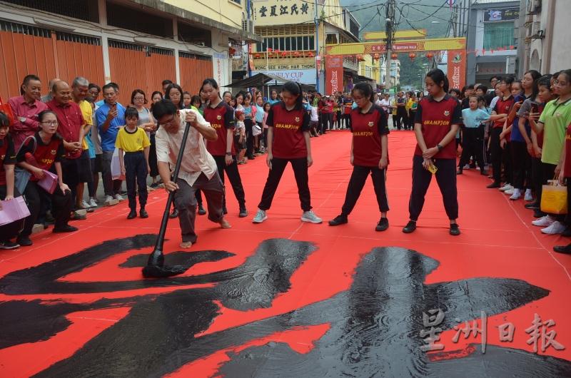 赵友福在巨幅红布挥春，吸引民众围观。（图：星洲日报）