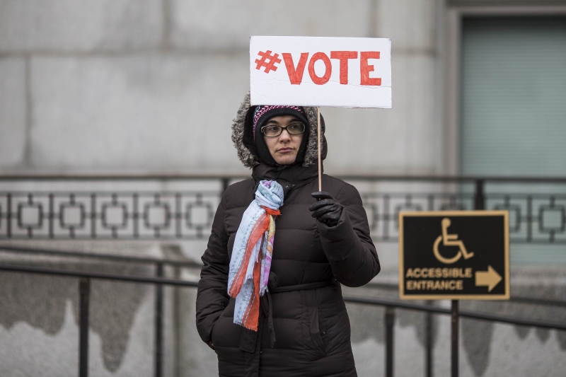 一名女子手持“#投票”的标语牌，呼吁人们在来临的总统选举中踊跃投票，下架特朗普。（图：法新社）