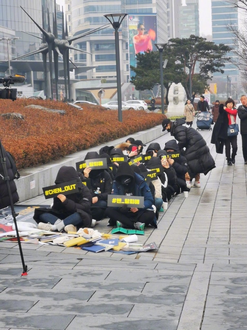 在EXO粉丝俱乐部预告将在19日举行要求EXO成员Chen退出组合的示威后，有约10余名粉丝粉现身SM公司门口拉横幅静坐。