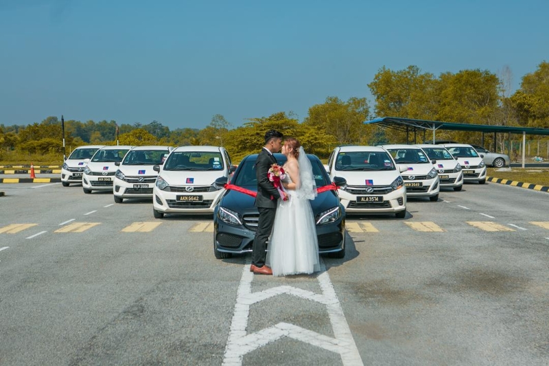 新郎李顺舜（左）与新娘盘淑莹在8辆Axia轿车前合照。
