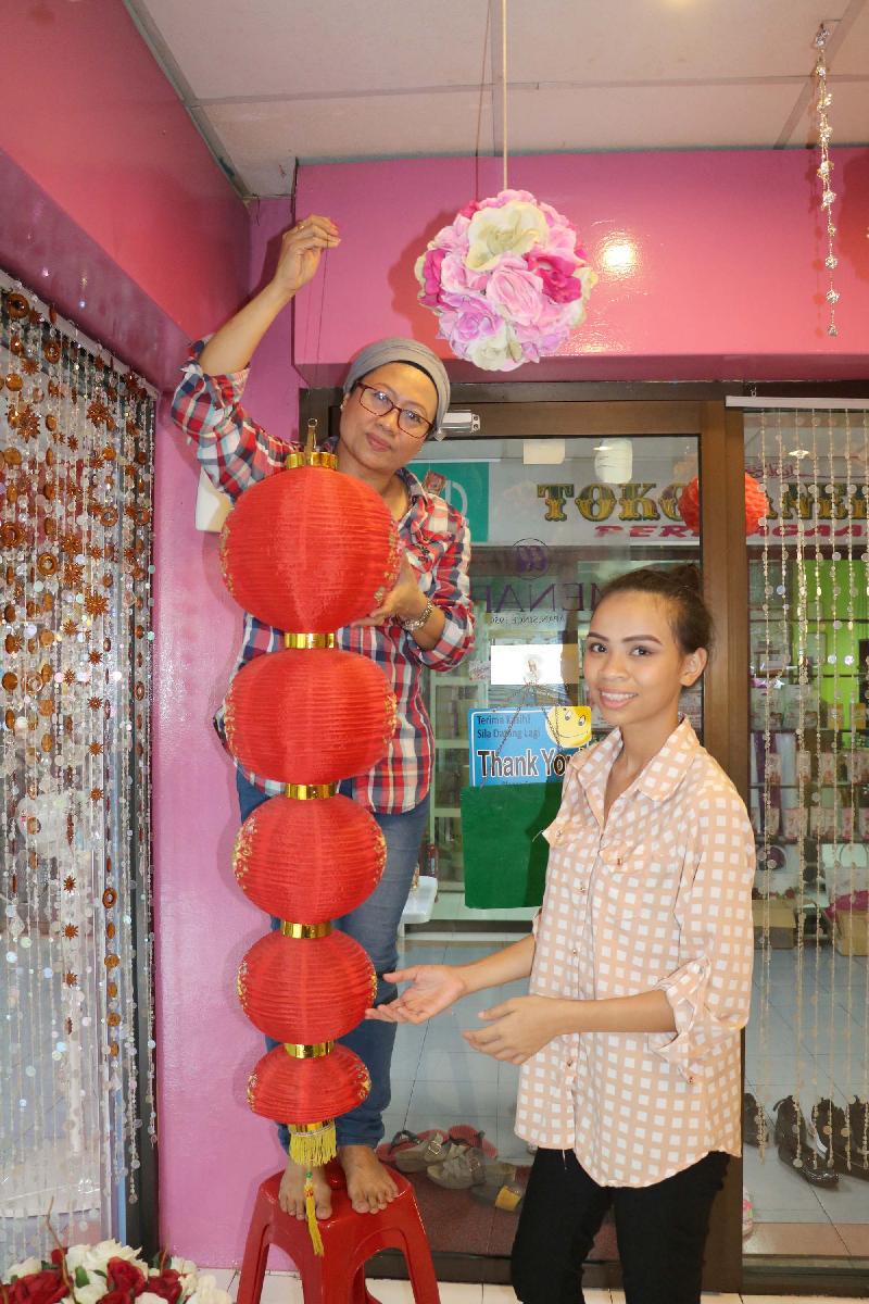 
巫裔女商人玛雅（左）和工人一起在店里挂起灯笼。