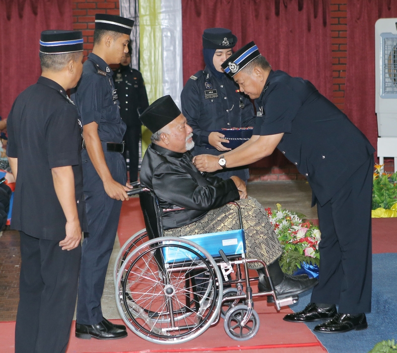 阿都哈密（右）颁发国家英雄有功奖章给一名坐在轮椅的普通行动部队队员。