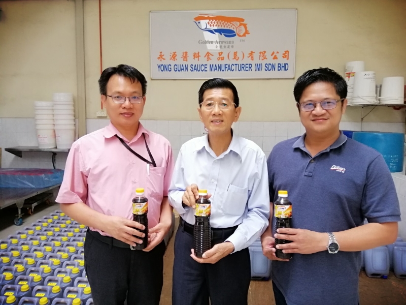永源酱料赞助150瓶金龙鱼商标顶生抽，礼品是由永源酱料董事经理刘福祥（中）移交。