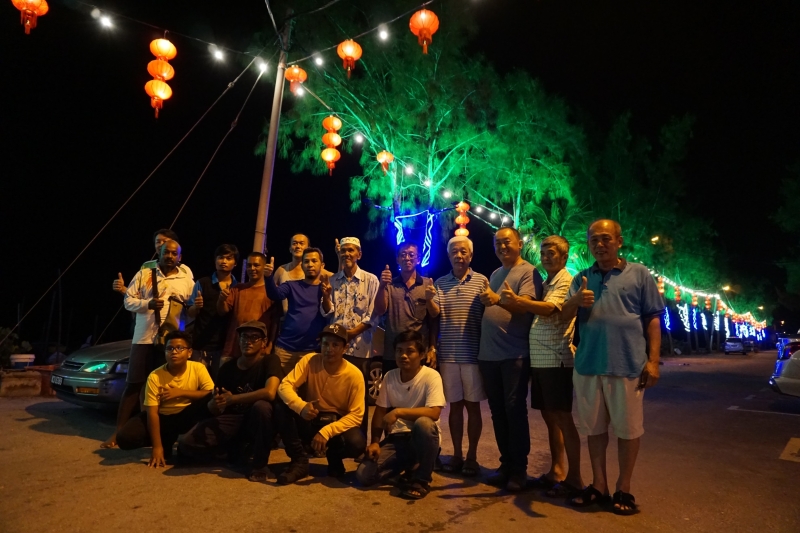 新甘光各族人民一齐庆祝不同的节日，图为新村晚会工委会秘书李玉泰(站者右一)与各族村民在五光十色的街道上合摄。

