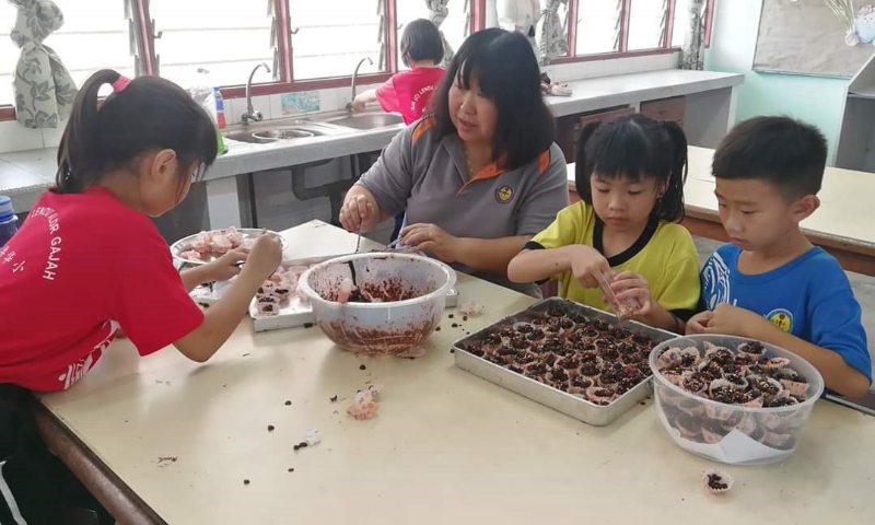 低年组的学生在教师姚玉莉的指导下制作年饼。

