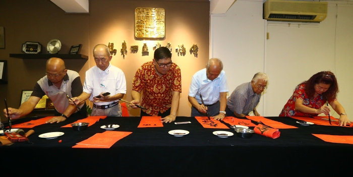 黄瑞庆（左三）率领马来西亚书艺协会一行人挥春。左起为工委郑添发和理事郭明丰；右起为工委陈玉凤、甄振球和会务顾问拿督斯里纪永辉。