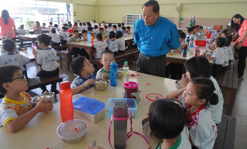 陳昱銘（站者）會到校與學生交流，鼓勵他們把營養餐吃完。