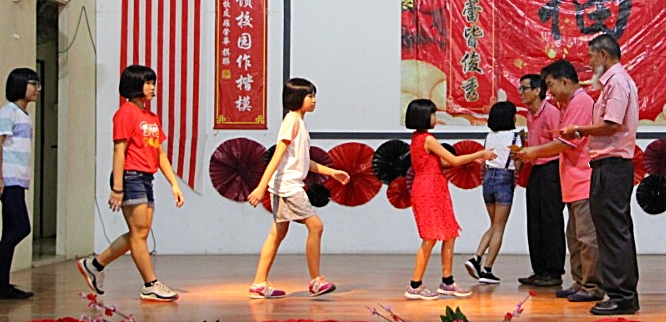 右起盧宇廷、杨业鸿和校友會主席周福禮派發紅包給學生。