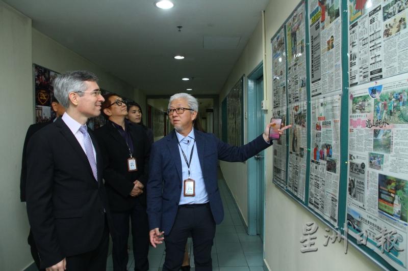 郭清江（右）带领庞维德（左）参观星洲日报编采部时，向他解说国内外重大事件的新闻报道剪报。