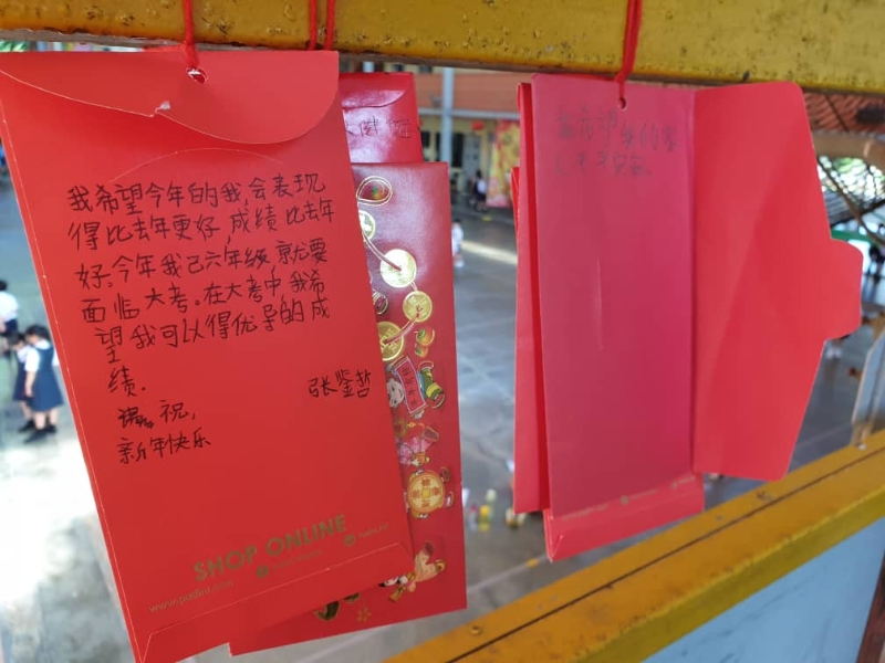 学生们发挥创意，以红包充作许愿纸条，许下新年愿望，悬挂在校园走廊栏杆上。