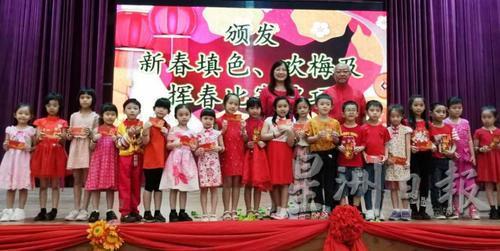 董事会副主席苏德招（后排右）在校长张毓殷（左）陪同下颁发红包予一二年级填色赛得奖同学。