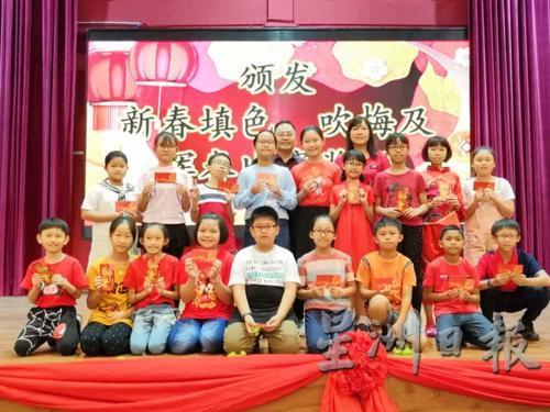 培一家协副主席谢德伟（后排左一）与张毓殷校长（后排右一）颁发红包予五六年级挥春比赛得奖的同学。
