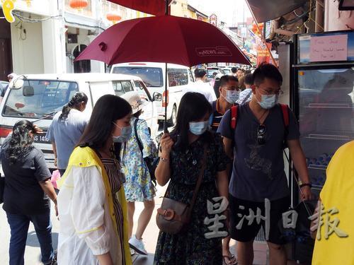 炎热天气，游客们撑伞及戴口罩。