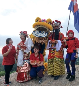 A Malay hiker (R) joins in the CNY celebration with the God and Goddess of Prosperity. SIN CHEW DAILY