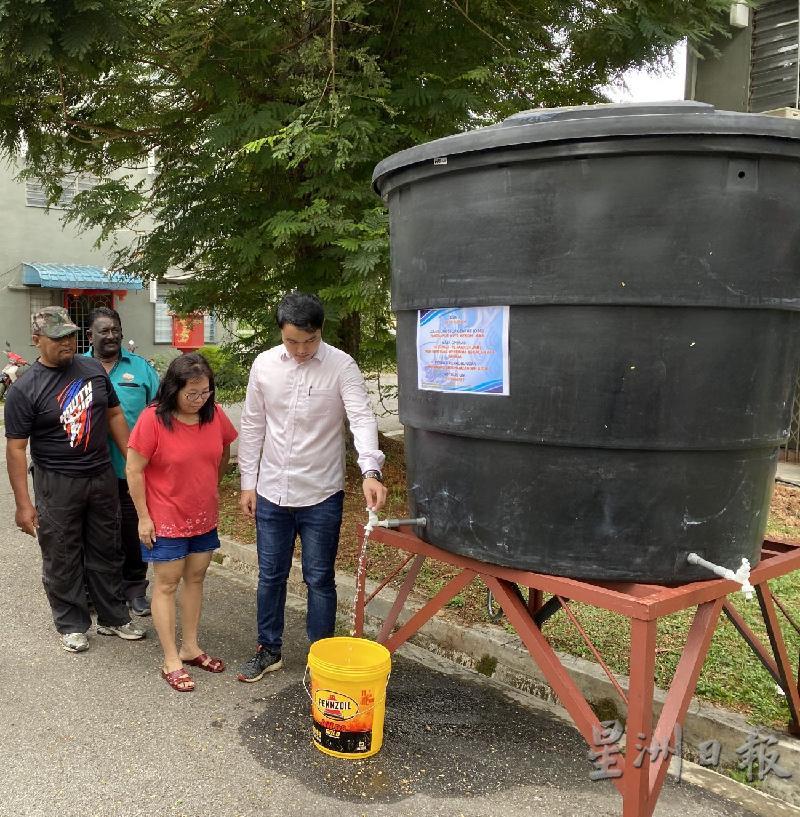 郭子毅（右一）协助居民取水，同时测试水供。