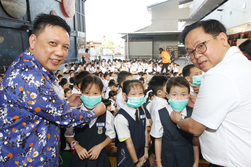 郑明发（左起）和梁德志分派口罩给学生，并向学生宣导预防武汉肺炎方法。