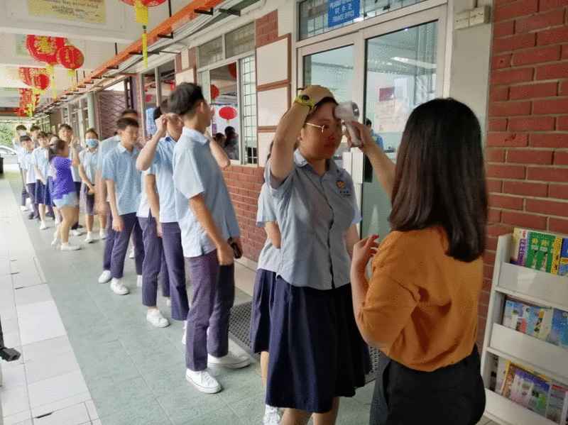 沙巴崇正中学学生排队接受体温检查。