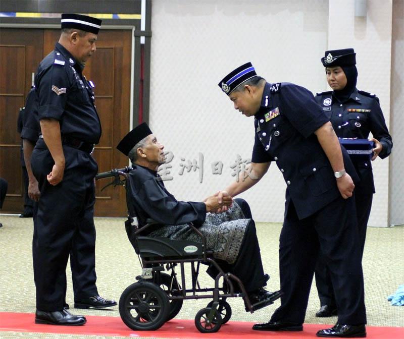 查卡利亚（右）颁发警察国家英雄勋章（PJPN）给一名行动不便的退休警员。