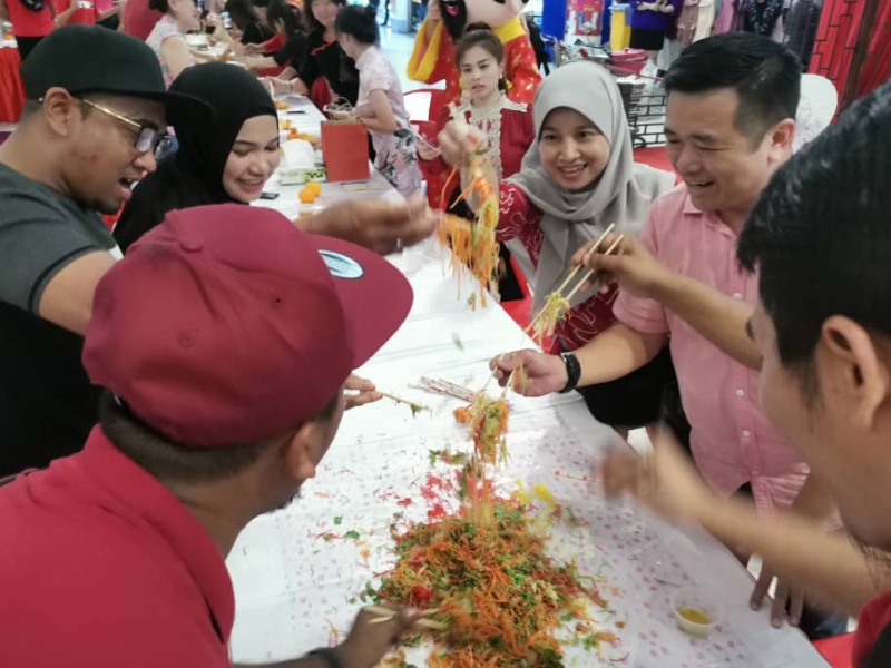 出席Angsana购物广场新春团拜的马来同胞和华裔一起捞生。