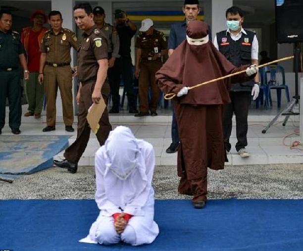 The first female flogger prepares to whip a woman in public in Banda Aceh for a morality crime. AFP