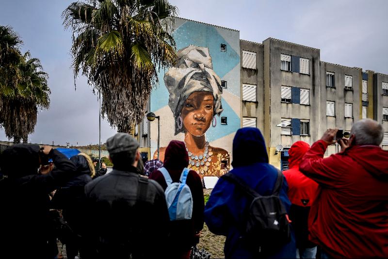 Visitors watch a mural by Uruguayan artist Maria Noe during a guided visit to the Quinta do Mocho neighborhood of Sacavem outside the Portuguese capital of Lisbon. AFP