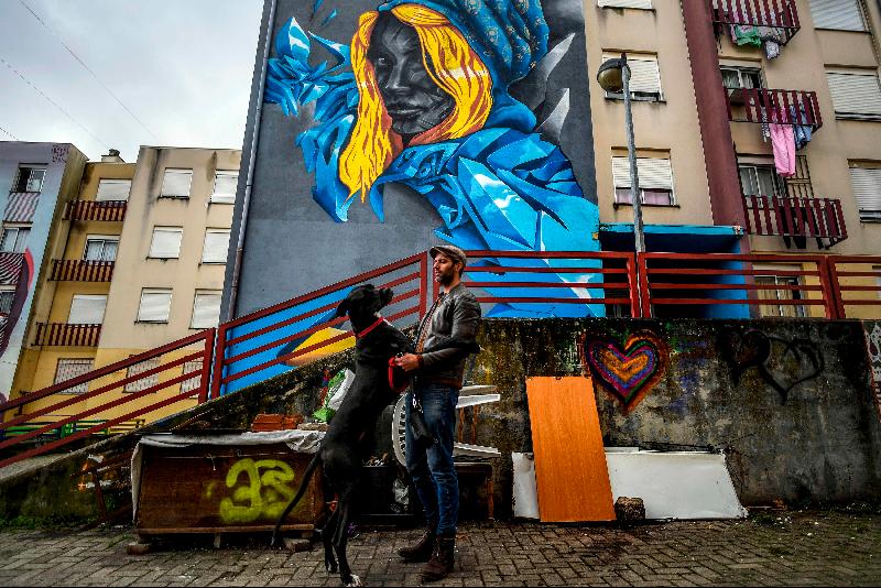 Portuguese artist Acer poses with his dog in front of his mural in Quinta do Mocho neighborhood of Sacavem outside the Portuguese capital of Lisbon. AFP