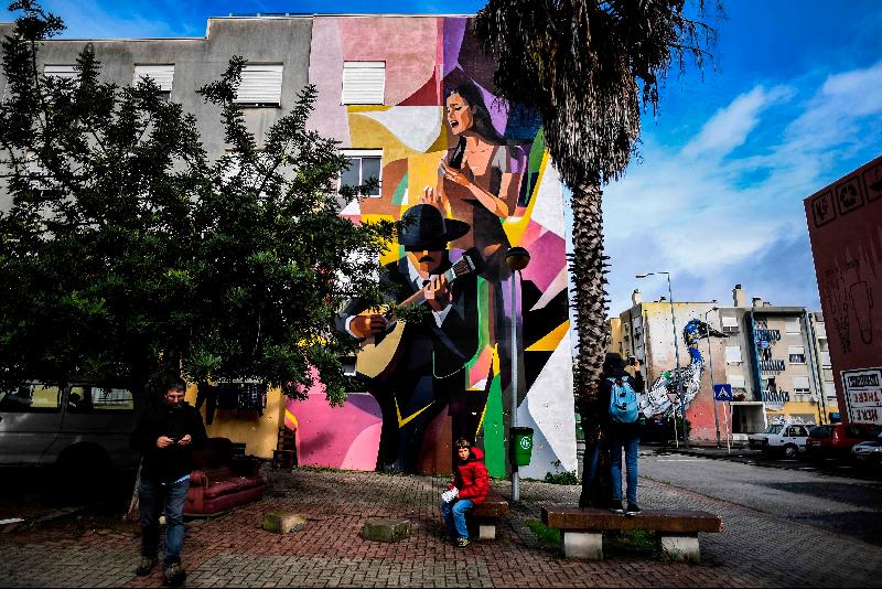 Visitors take pictures of a mural by Russian artist Zmock (L) and Portuguese artist Bordalo II (R) during a guided visit to the Quinta do Mocho neighborhood of Sacavem outside the Portuguese capital of Lisbon. AFP