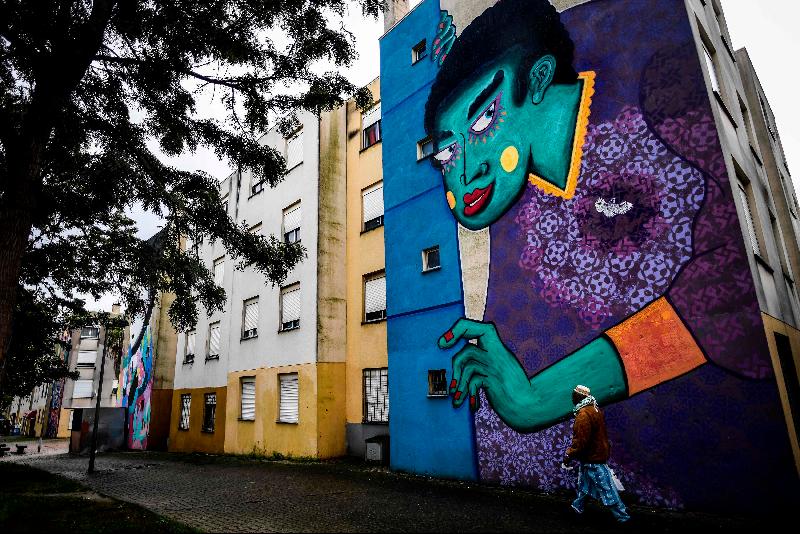 A resident walks past a mural by French artist Stew in Quinta do Mocho neighborhood of Sacavem outside the Portuguese capital of Lisbon. AFP