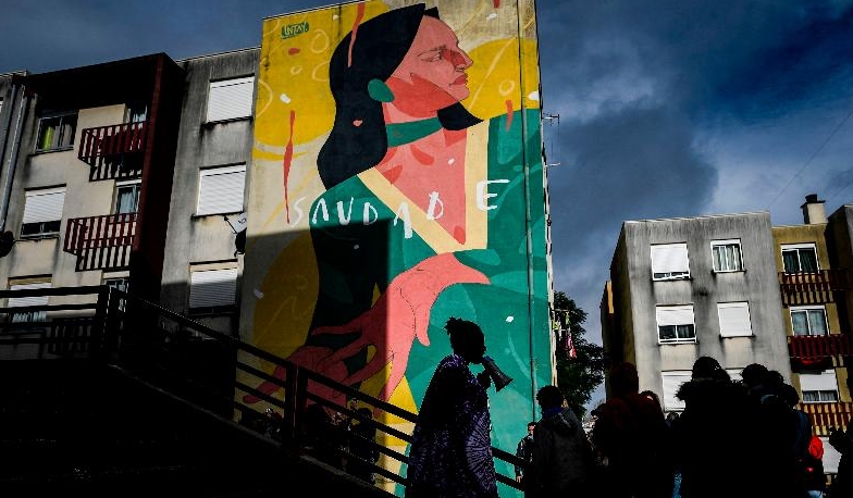 People stand in front of a mural by Israeli artist Untay during a guided visit to the Quinta do Mocho neighborhood of Sacavem outside the Portuguese capital of Lisbon. AFP