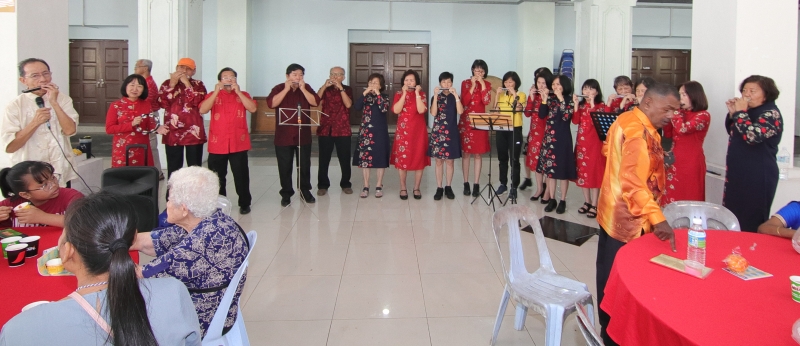 关丹和声口琴队约20名表演者在指导老师许华恩（站者左一）指挥下，为正在用餐的民众带来一支支悠扬悦耳的口琴演出。