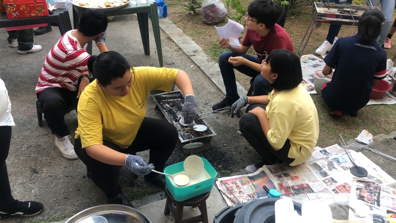 学生们在老师带领下，亲手制作鸡蛋饼（Kuih Kapit），吸引许多学生排队品尝。