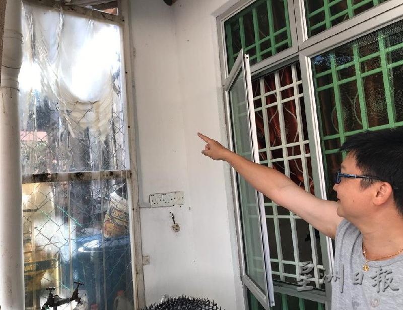 郑荣鑫指住家外的篱笆塑料板已被大火烧损变形。