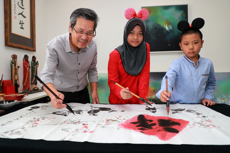 吴亚鸿（左起）与巫裔学生阿菲花和孙子吴昱贤联合创作新春鼠画，展现和谐之美。