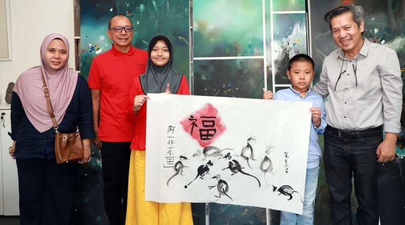 吴亚鸿（右一起）与孙子吴昱贤和巫裔学生努阿菲花，联合创作出一幅展现和谐福气的新年鼠画。左一起阿菲花母亲都迪卡蒂尼和父亲凯鲁安努亚。