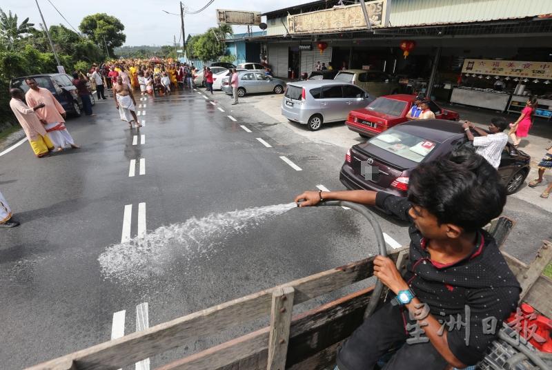 游行队伍途经的街道，须先经过清水洒净。（图：星洲日报）
