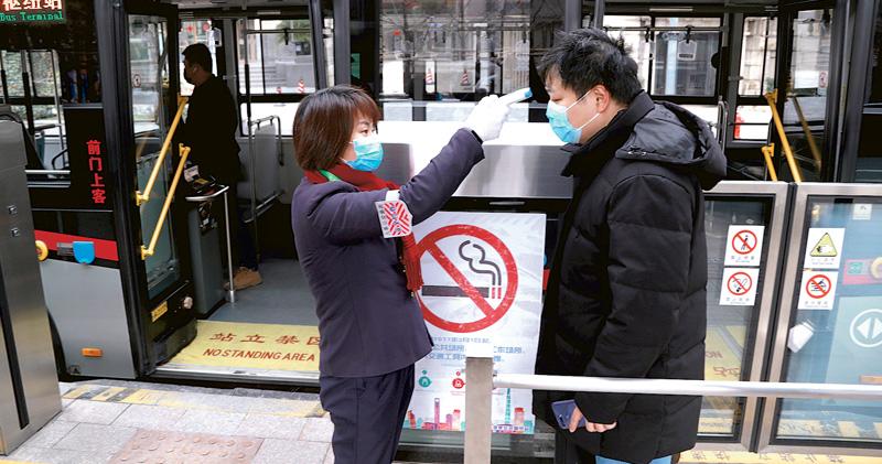 上海8日严格执行公共场所体温检测和自觉佩戴口罩措施，拒不配合者，工作人员可拒绝其进入。图为工作人员在公交车站为乘客测量体温。（图：中新社）