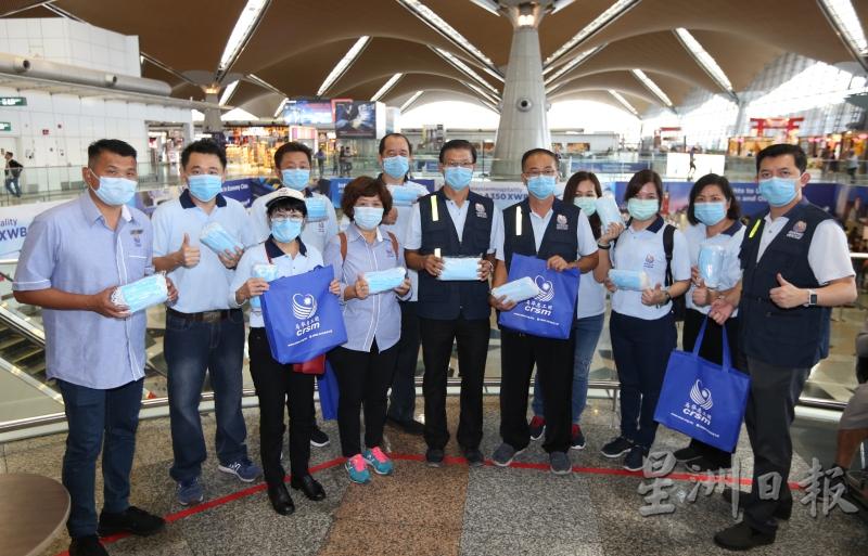 庄赐昭（左七）及罗秀英（左五）带领该团团员在吉隆坡国际机场派发1000个口罩。