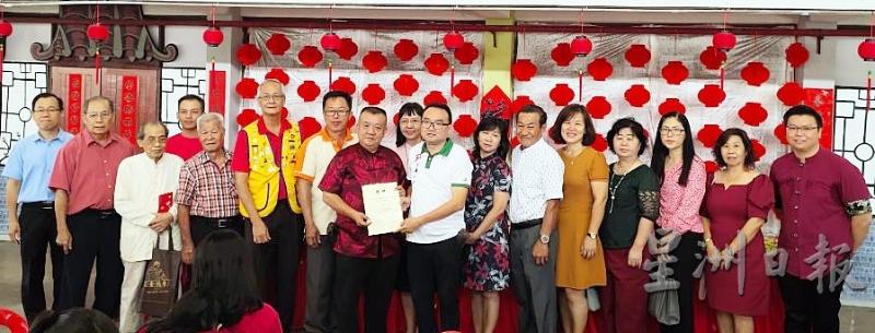 刘纬雄（右八）移交感谢状给开幕人刘添财代表刘宝华，左起李世坚、黄有为、罗肇华、罗止君、陈联德、谢其旺和俞秀君，右起是黄伟伦、李慧婷、何淑仪、苏秀兰、梁玮玲、徐忠善、王保月和莫碧英。（图：星洲日报）