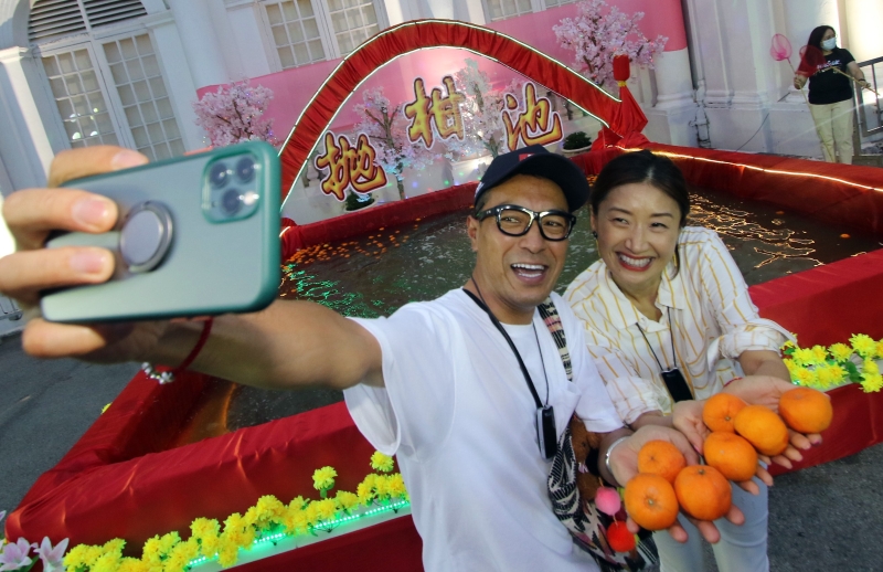 旅居槟城的港星黑仔姜皓文（左起）和太太殷宁也到旧关仔角体验槟城人的元宵庆典