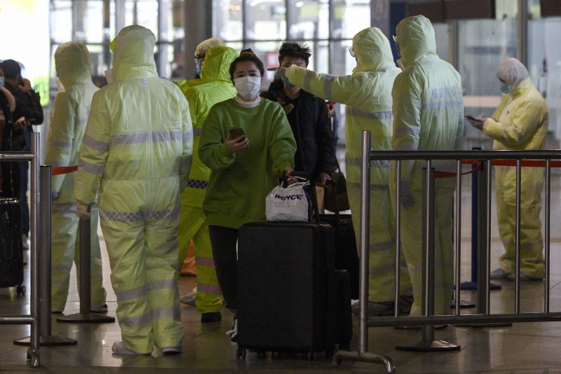 身穿防护服的医务人员星期日在上海南站检查回来准备复工的乘客的旅行史。（法新社照片）