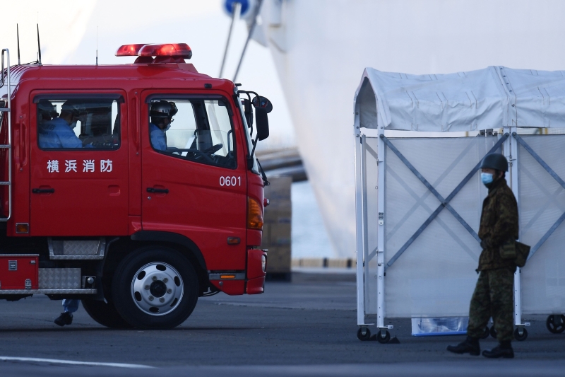 “钻石公主号”周一再确诊60宗新完肺炎病例。图为在邮轮停靠的日本横滨港，可见一名士兵和一架消防车在港口 待命。（法新社照片）