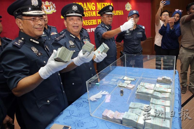 弗亚（左起）、莫哈末沙比林和诺依斯迈向媒体展示起获疑似用来洗黑钱的约50万现金，大部分是马币，也有泰铢。